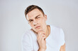 © SHOTPRIME STUDIO - Emotional man in a white t-shirt holds his hand on his face light background