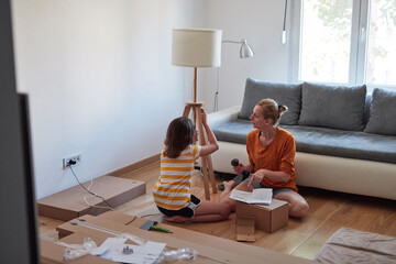 Wall Mural - Mother and daughter assembling new furniture - moving in into a new home.