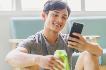 Canvas Print - Asian man resting and using phone after exercising