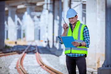 Wall Mural - Portrait engineer under inspection and checking construction process railway and checking work on railroad station .Engineer wearing safety uniform and safety helmet in work.