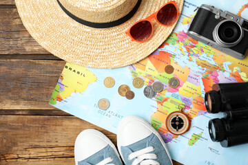 Wall Mural - Flat lay composition with world map and different travel accessories on wooden table. Planning summer vacation trip