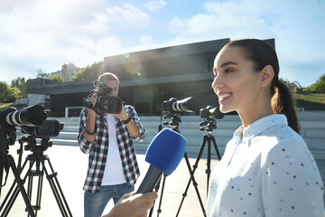 Professional journalist and operator with video camera taking interview outdoors