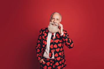 Sticker - Photo of cheerful pensioner man hold telephone talk look empty space wear heart print suit tie isolated red background