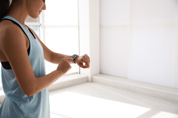 Wall Mural - Woman checking fitness tracker in gym, closeup. Space for text