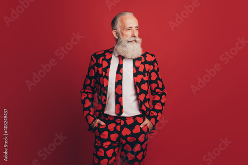 Photo of self-assured bearded man hands pockets cool look side empty space wear heart print tux isolated red background © deagreez