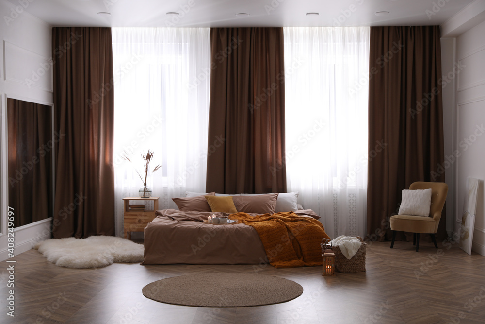 Bed with brown linens in stylish room interior - obrazy, fototapety, plakaty 