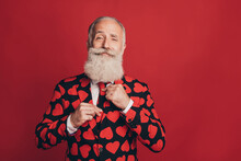 Photo Of Bearded Gentleman Adjust Tie Self-assured Look Camera Wear Heart Print Suit Isolated Red Background