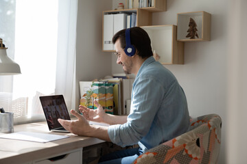 Wall Mural - corporate meeting online. confident businessman sit by laptop in headphones negotiating with partner
