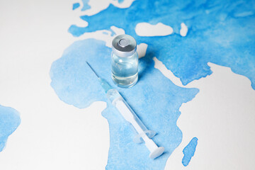bottle of coronavirus vaccine and syringe on world map background. science laboratory research, vacc