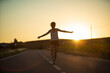 © Xavi Lapuente - Young girl, walking in the middle of a lonely straight road, late in the day. With the hands stretched out in the shape of a cross, to maintain balance and not fall from the dividing line.