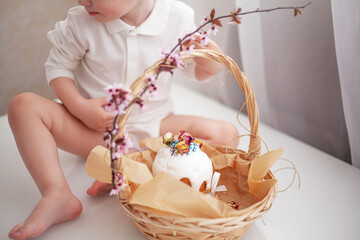 Wall Mural - The kid eating traditional russian easter cake on table. The decorarion of kulich are the flower are cooking for spring holiday