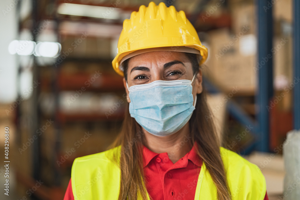 Happy Latin woman working in warehouse while wearing face mask during corona virus pandemic - Logistic and industry concept - obrazy, fototapety, plakaty 