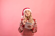 © Prostock-studio - Charming young lady in Christmas outfit thinking about her New Year resolutions, writing wish list over pink background