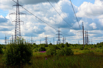 Power line in the countryside. High-voltage poles stretch along the forest. Electric poles.