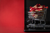 Fototapeta Tęcza - Online shopping for Valentine's day concept - presents in shopping cart, red background