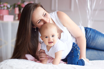 Happy family. Mother with her little baby in light interior livihg room. Mother's day celebration with gifts and flowers