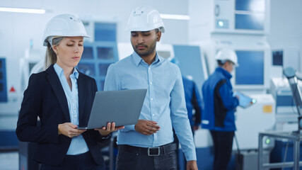 Poster - Chief Engineer and Project Manager Wearing Safety Vests and Hard Hats, Use Laptop in Modern Factory, Talking, Optimizing Production Line. Industrial Facility: Professionals Working on Machinery