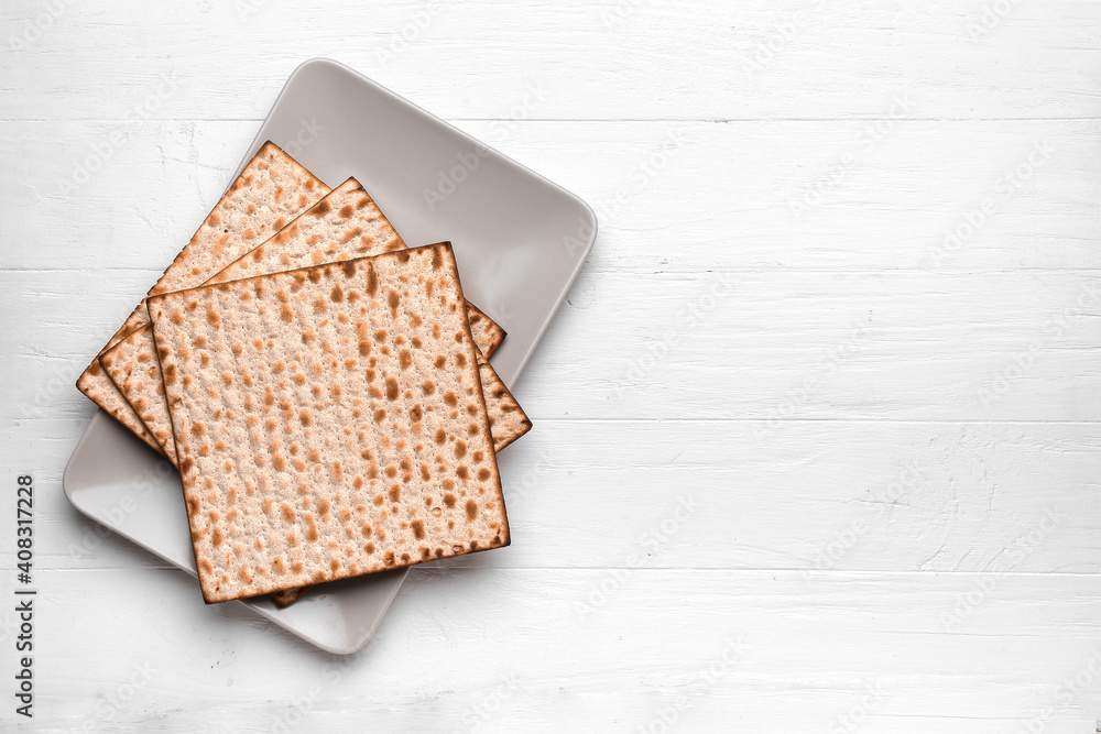 Plate with Jewish flatbread matza for Passover on white wooden background
