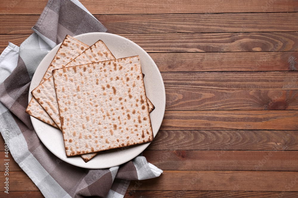 Plate with Jewish flatbread matza for Passover on wooden background