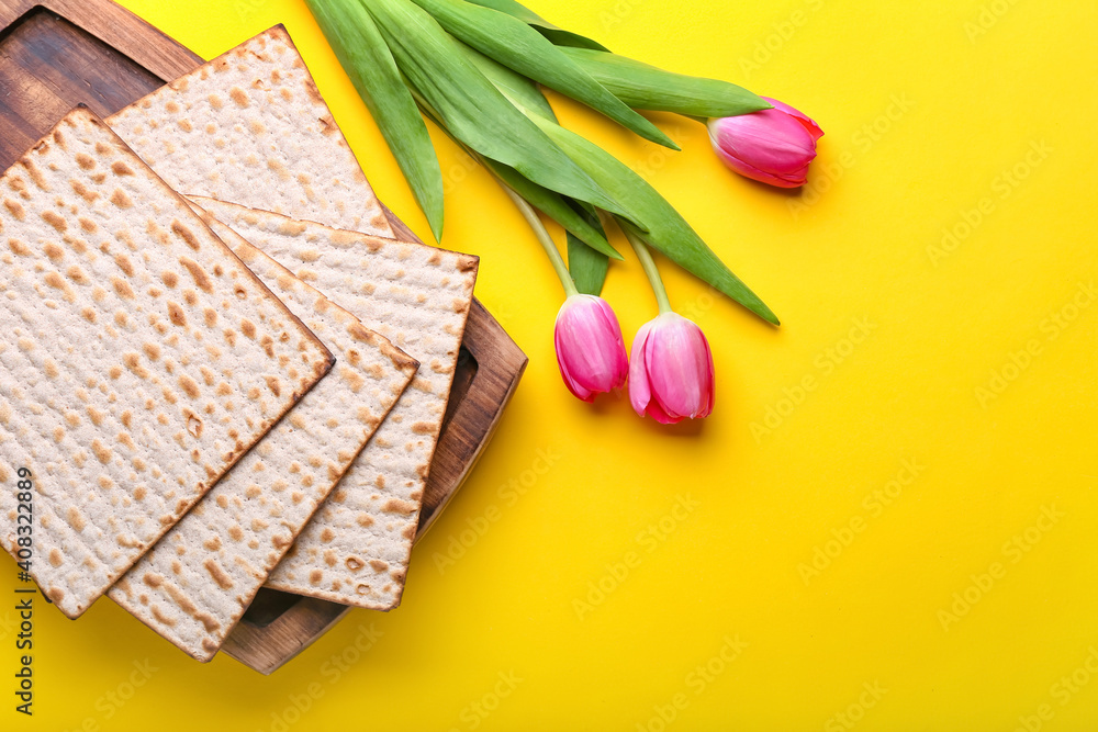 Jewish flatbread matza for Passover and flowers on color background