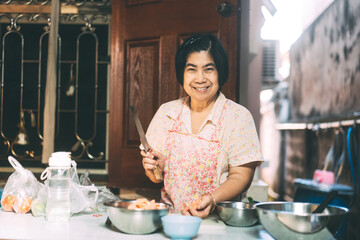 Aunthentic portrait of happy asian elderly woman cooking for family at local traditional kitchen style at home.