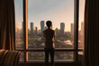© Mumemories - Young asian man standing and looking through window in a hotel. Sunrise over modern buildings in Songdo central park