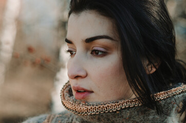 Wall Mural - Close up portrait of a brunette woman looking to the side, neutral expression, dressed in a cosy, warm sweater.