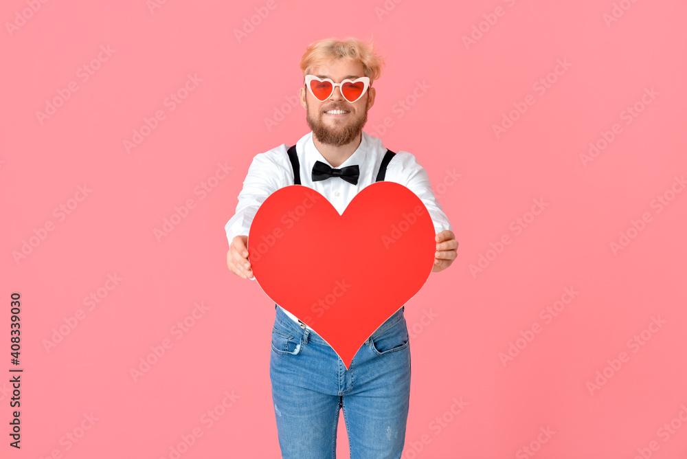 Handsome man with big red heart on color background
