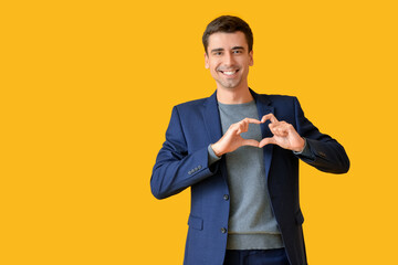 Poster - Handsome man making heart with his hands on color background