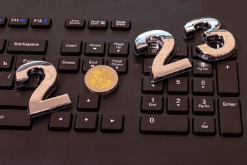 Wall Mural - black keyboard. close-up. on it are laid out numbers of metal 2023 in the center of the coin 2 euro