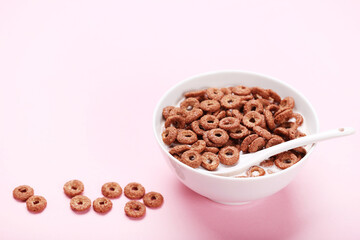 Poster - Chocolate corn flakes in bowl with milk and spoon on pink background