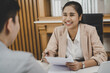 © KMPZZZ - Happy, Smiling asian manager, employer woman interview with young man, have question about resume and listen to candidate answers, conversation together at office. Recruitment employee job concept.