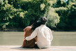 © Dearix - A sweet couple of teenage sitting on bridge, asian man with white shirt hug or cuddle a young woman with brown dress.   Romantic mood and sweet emotional relationship in summer with copy space