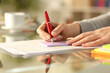 © PheelingsMedia - Woman hand writing on sticky note on a table at home