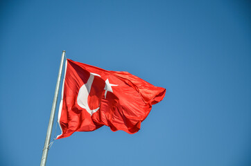 National Turkish red flag with white crescent and star Waving in the wind on a clear blue sky background