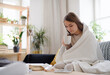 Ill young woman with blanket drinking tea at home, coronavirus concept.