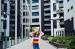 © Halfpoint - Portrait of young woman standing outdoors by block of flats in city.