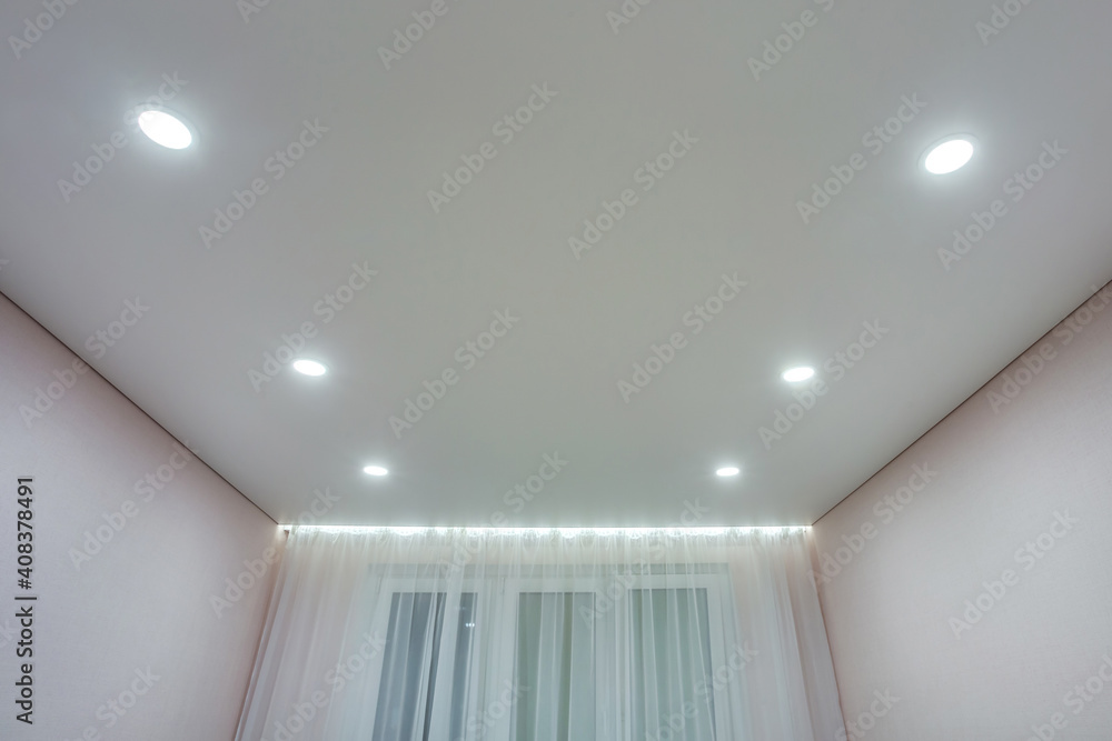suspended ceiling with halogen spots lamps and drywall construction in empty room in apartment or house. Stretch ceiling white and complex shape. - obrazy, fototapety, plakaty 