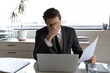 Close up unhappy businessman covering face with hand, reading bad news in letter, holding paper sheet, sitting at desk in office, frustrated employee received bank or job dismiss notification