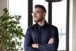 © fizkes - Head shot portrait close up dreamy smiling Arabian businessman wearing glasses looking to aside, standing with arms crossed in office, leader executive dreaming about good future, new opportunities