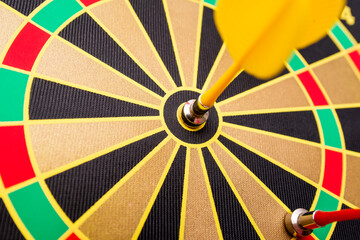 Closeup of a dartboard with yellow and red magnetic darts. Dart in bulls eye of dartboard concept for hitting target dart success concept