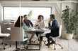 © fizkes - Diverse business people partners discussing project, contract terms, brainstorming in modern board room behind glass wall, colleagues sitting at table in office, talking, sharing startup ideas