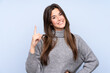 © luismolinero - Teenager Brazilian girl over isolated blue background showing and lifting a finger in sign of the best