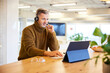 © Jo Kirchherr/Westend61 - Businessman wearing headset using digital tablet while sitting at office