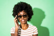 © Giorgio Fochesato/Westend61 - Woman adjusting sunglasses while standing against green background