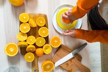 Woman Preparing Orange Juice On Juicer While Standing By Table At Home