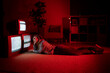 © Giorgio Fochesato/Westend61 - Young woman with hand in hair lying on floor in front of old TV's at living room