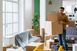 © Giorgio Fochesato/Westend61 - Smiling young man carrying cardboard boxes in living room of new apartment