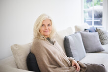 Beautiful Senior Woman With Long White Hair Sitting On Sofa In Living Room At Home