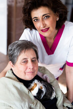 Female Caregiver With Disabled Woman Holding Guinea Pig At Rehabilitation Center